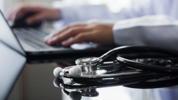 Man with stethoscope looking at laptop