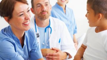 Male doctor with 2 female nurses examining a boy