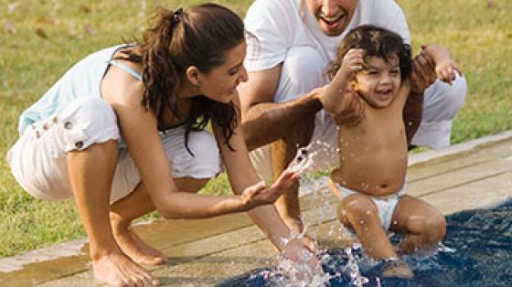 Mother and father playing with their toddler in a pool