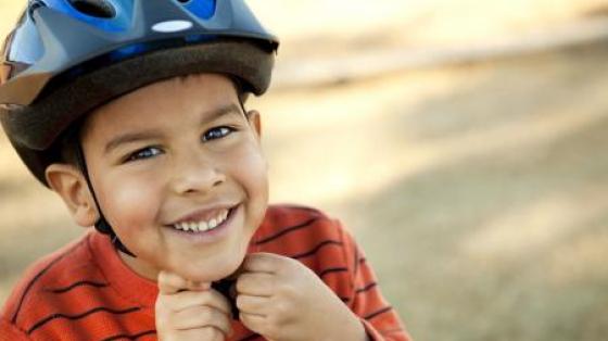 Young boy putting on his helmet