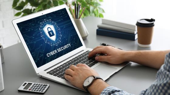 person on laptop that says "cybersecurity" on screen