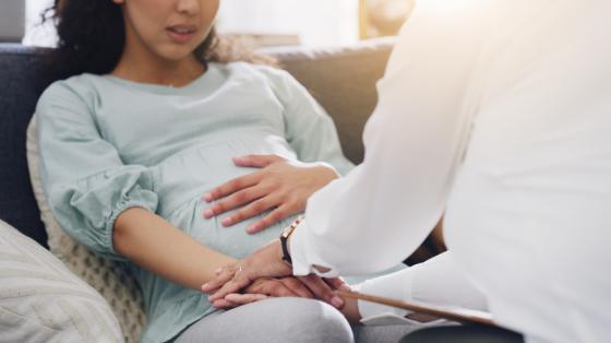 Pregnant woman holding hands with another person