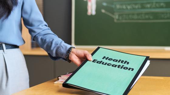 woman holding folder titled "Health Education"