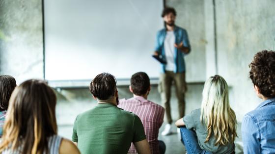 Male lecturing in front of a crowd